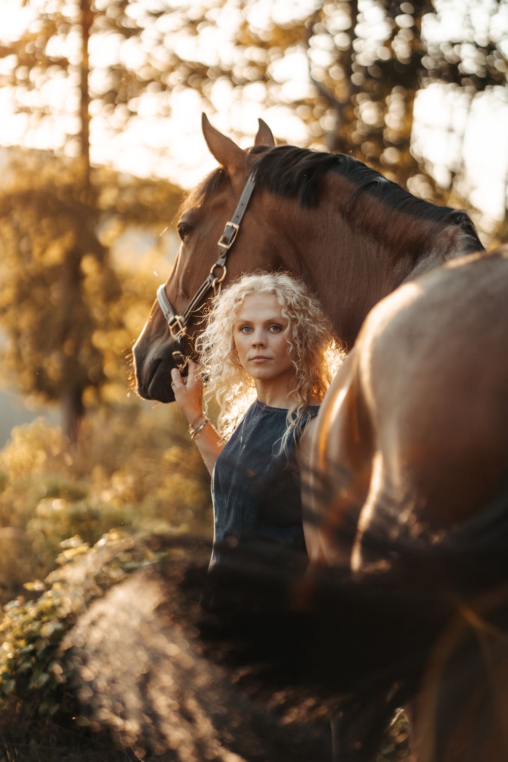 Frau mit Pferd zwischen Bäumen