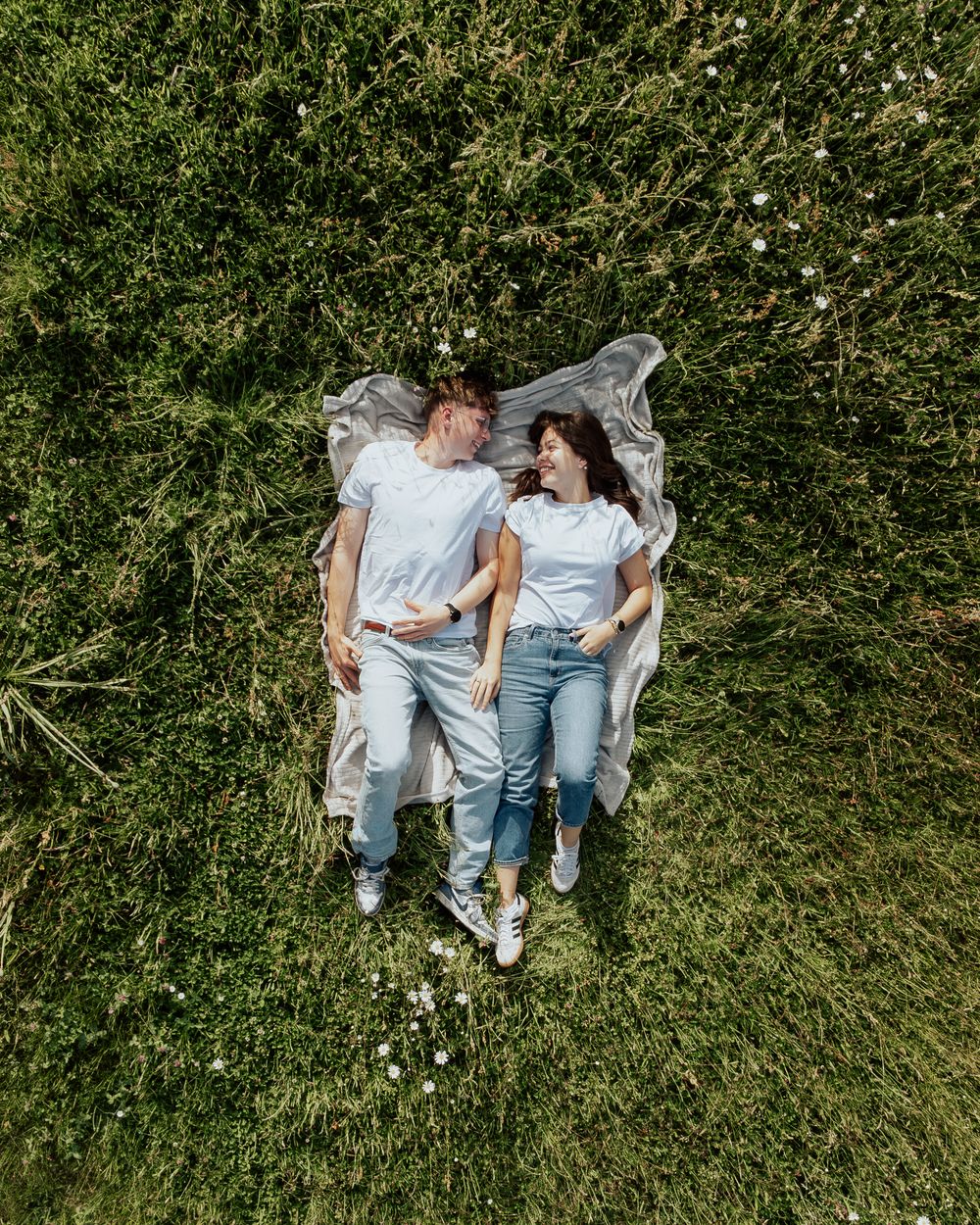 Paar liegt im Gras, von oben fotografiert
