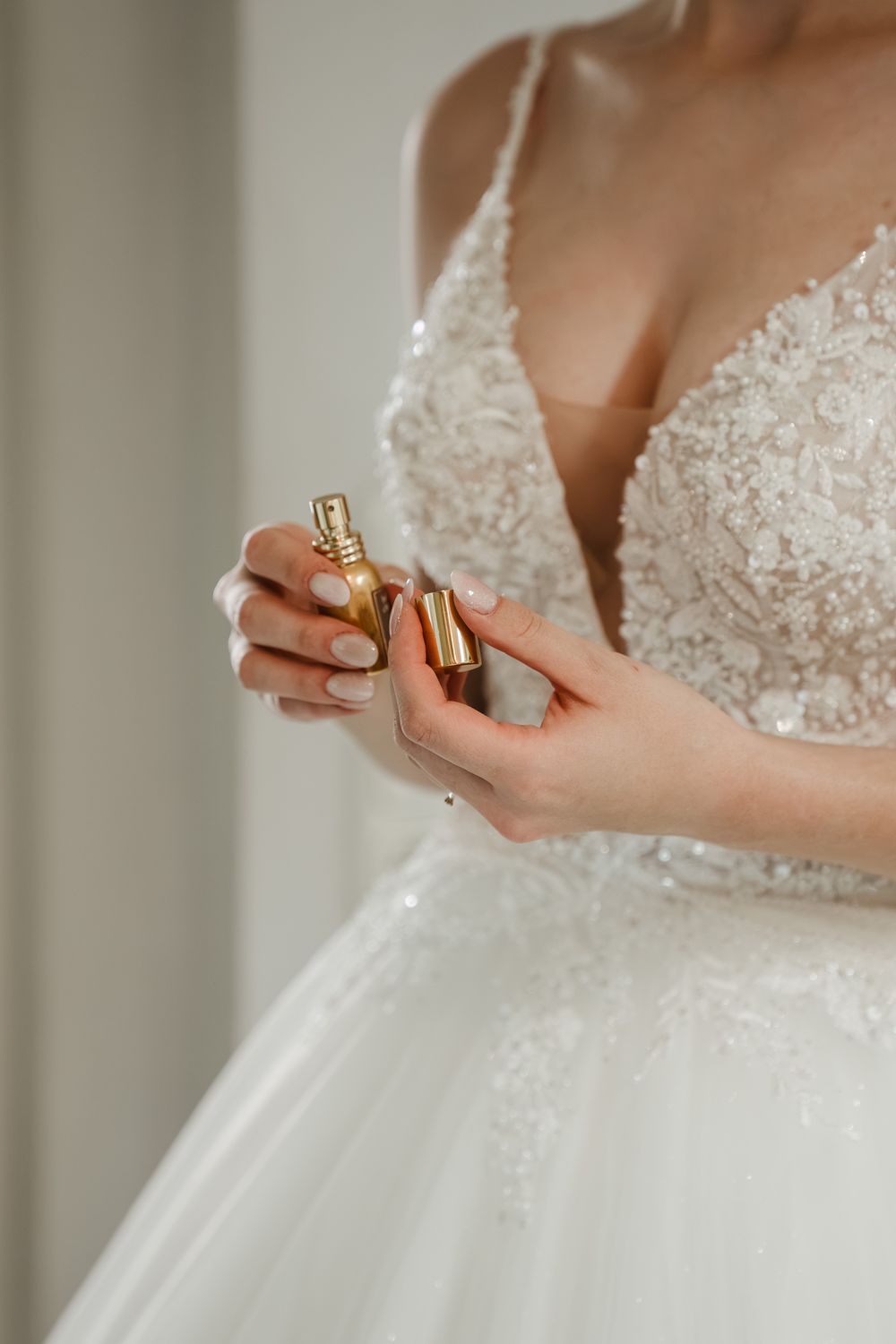 Braut mit Parfumflakon beim Anziehen