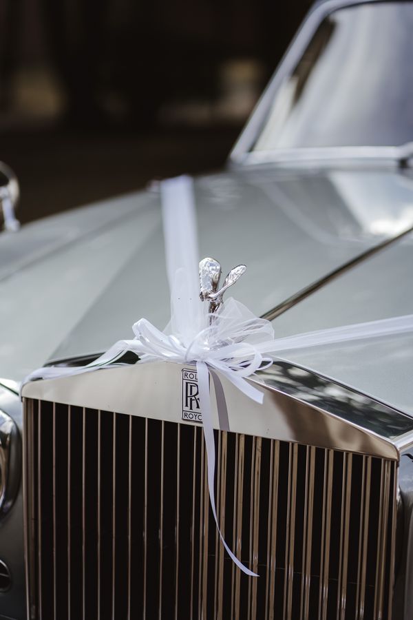 Kühlerfigur eines Rolls-Royce mit weißer Schleife