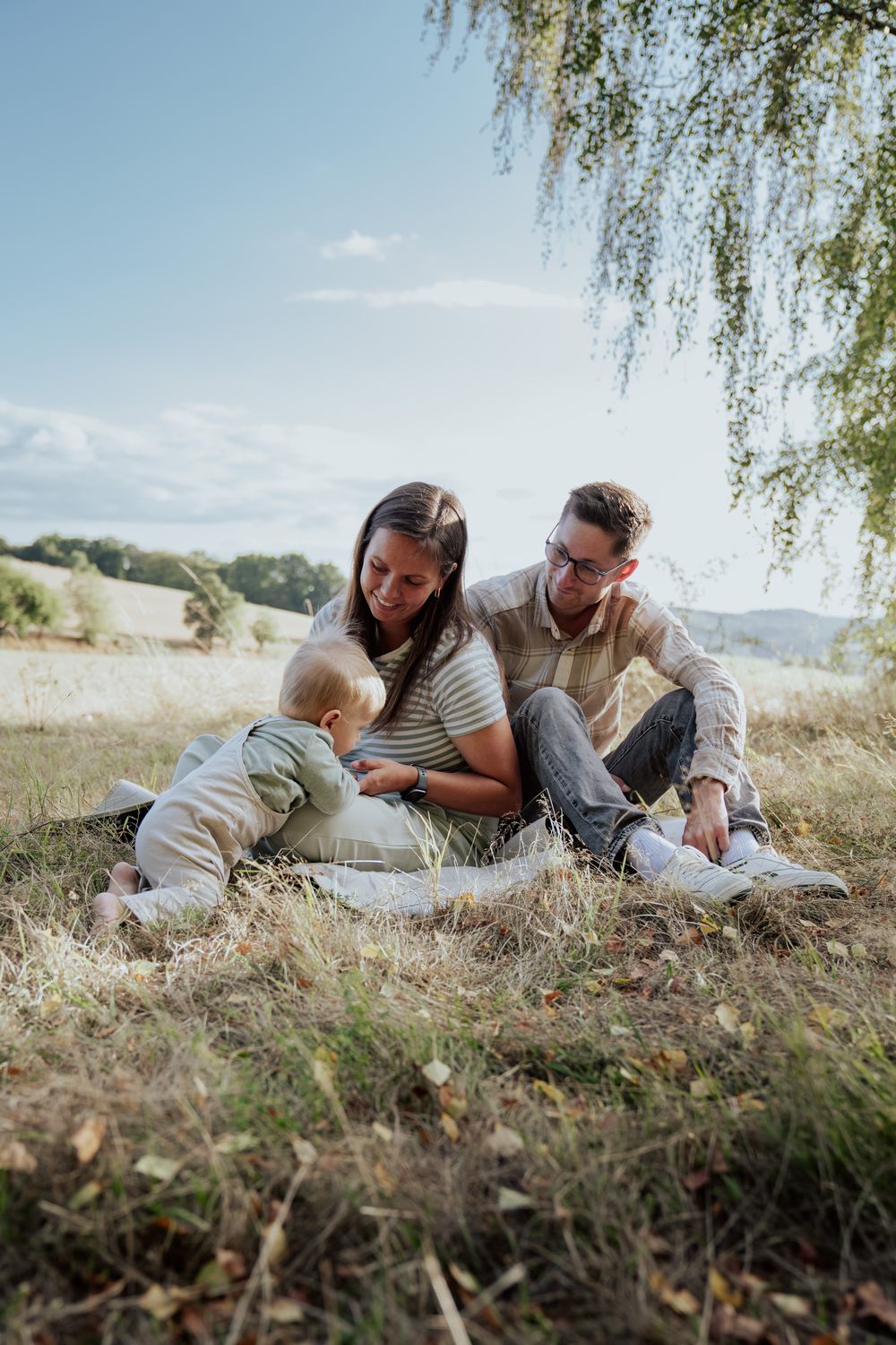 Familie mit Baby auf einer Decke im Gras