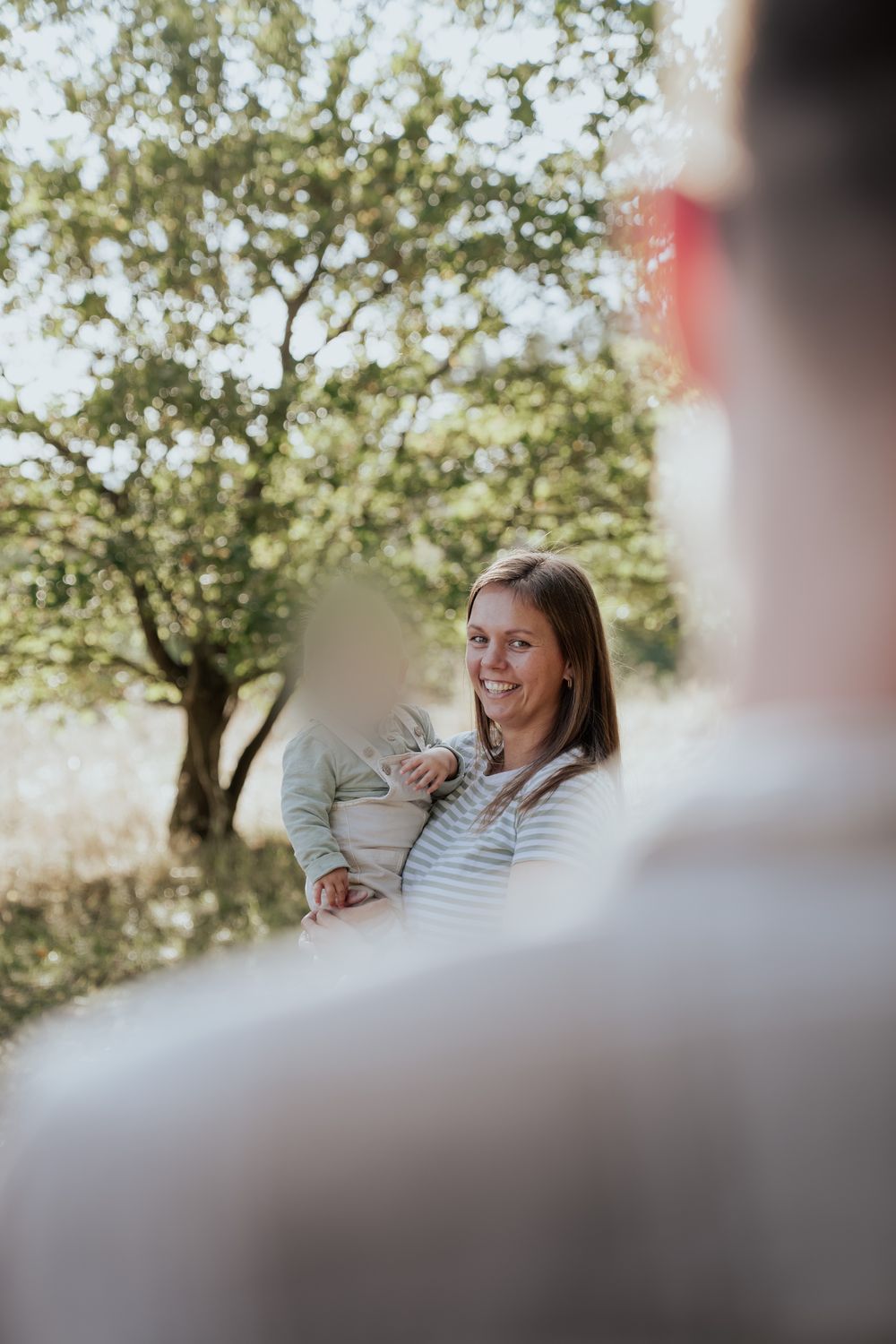 Mama mit Baby, unscharf im Vordergrund der Papa