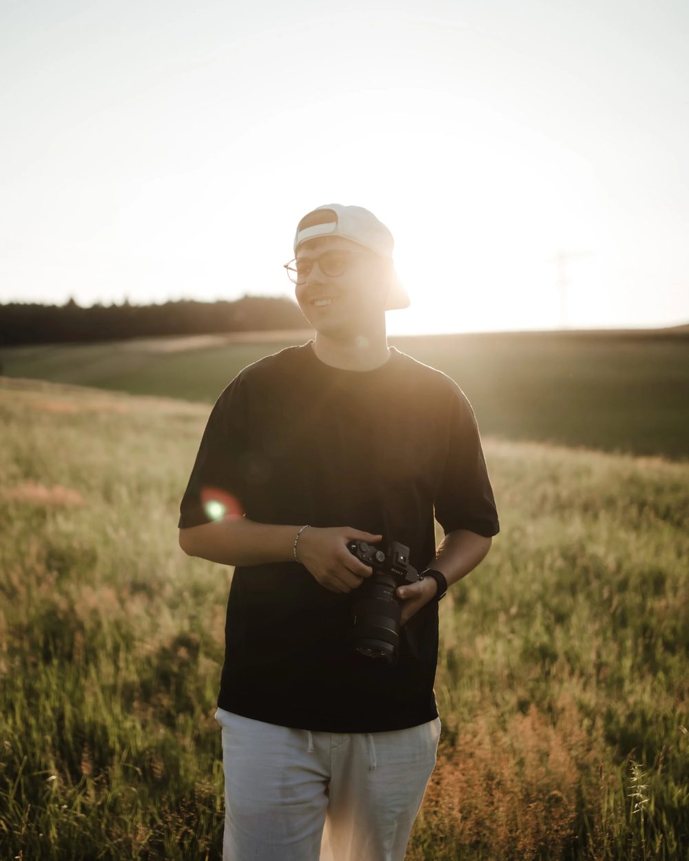 Luis Müller mit Kamera im Feld bei Sonnenuntergang